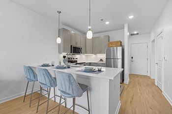 A kitchen with a white counter and blue chairs.